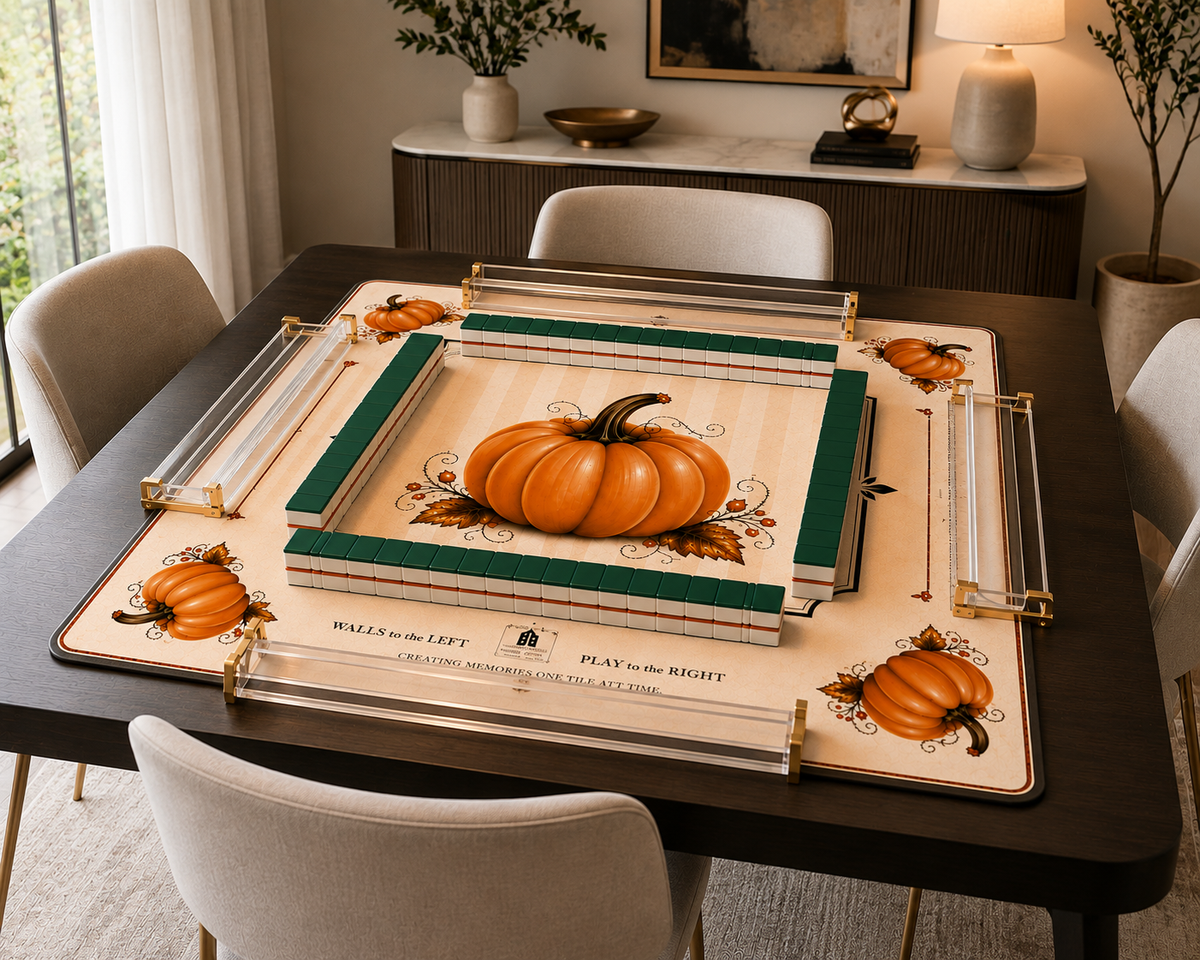 A decorative tabletop game board set displayed on a dark wood dining table in a styled dining room. The set includes a cream-colored board with orange pumpkins, green borders, and clear acrylic game pieces with gold-toned hardware.